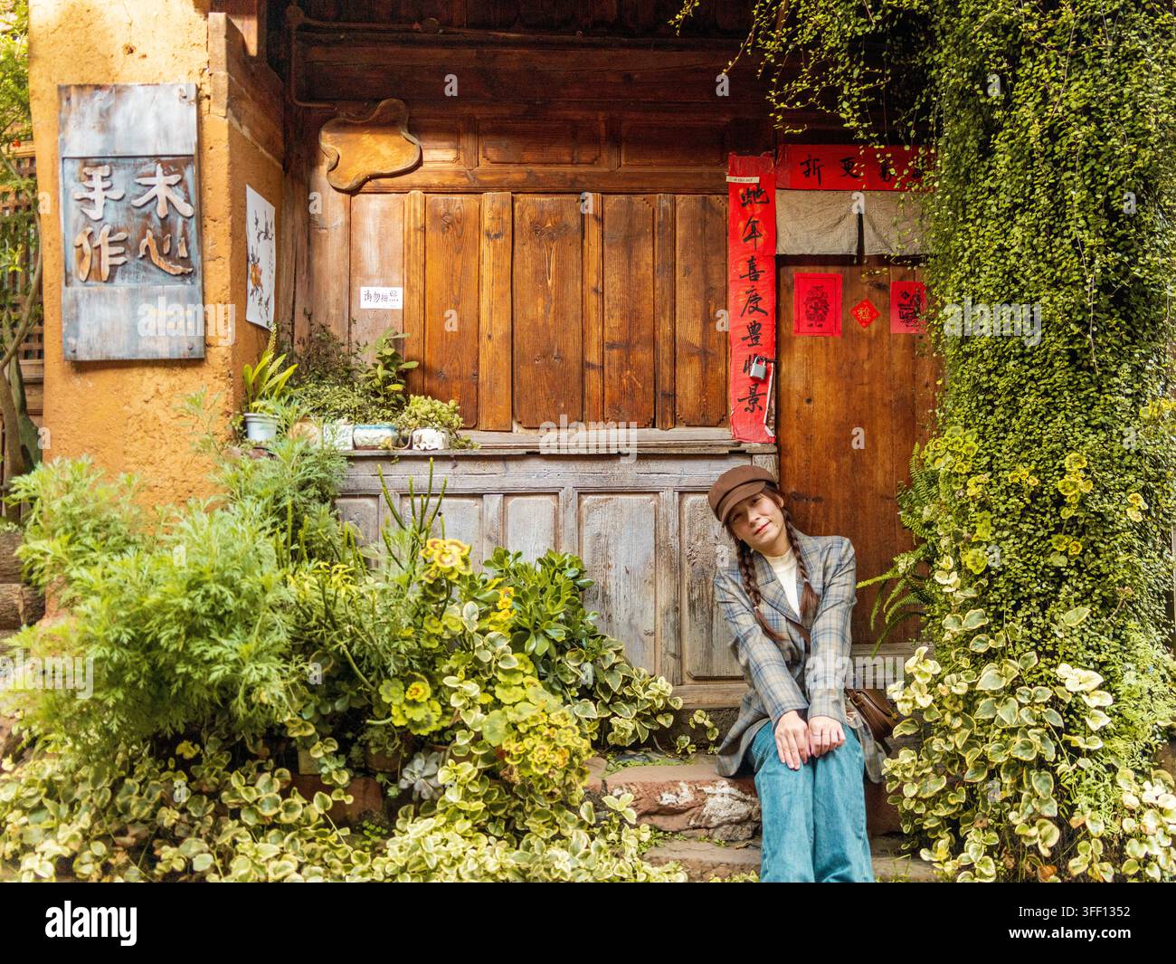 Donna sorridente sulla soglia della porta decorata con coppie rosse, Antica Città di Shaxi, Yunnan, Cina Foto Stock
