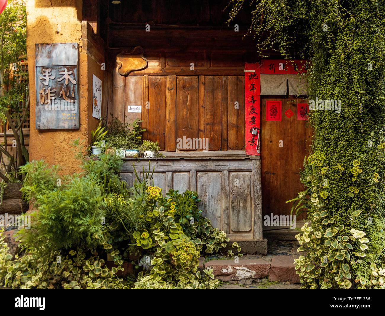 Portale in legno decorato con versi a coppie rossi e piante rampicanti, antica città di Shaxi, Yunnan, Cina Foto Stock
