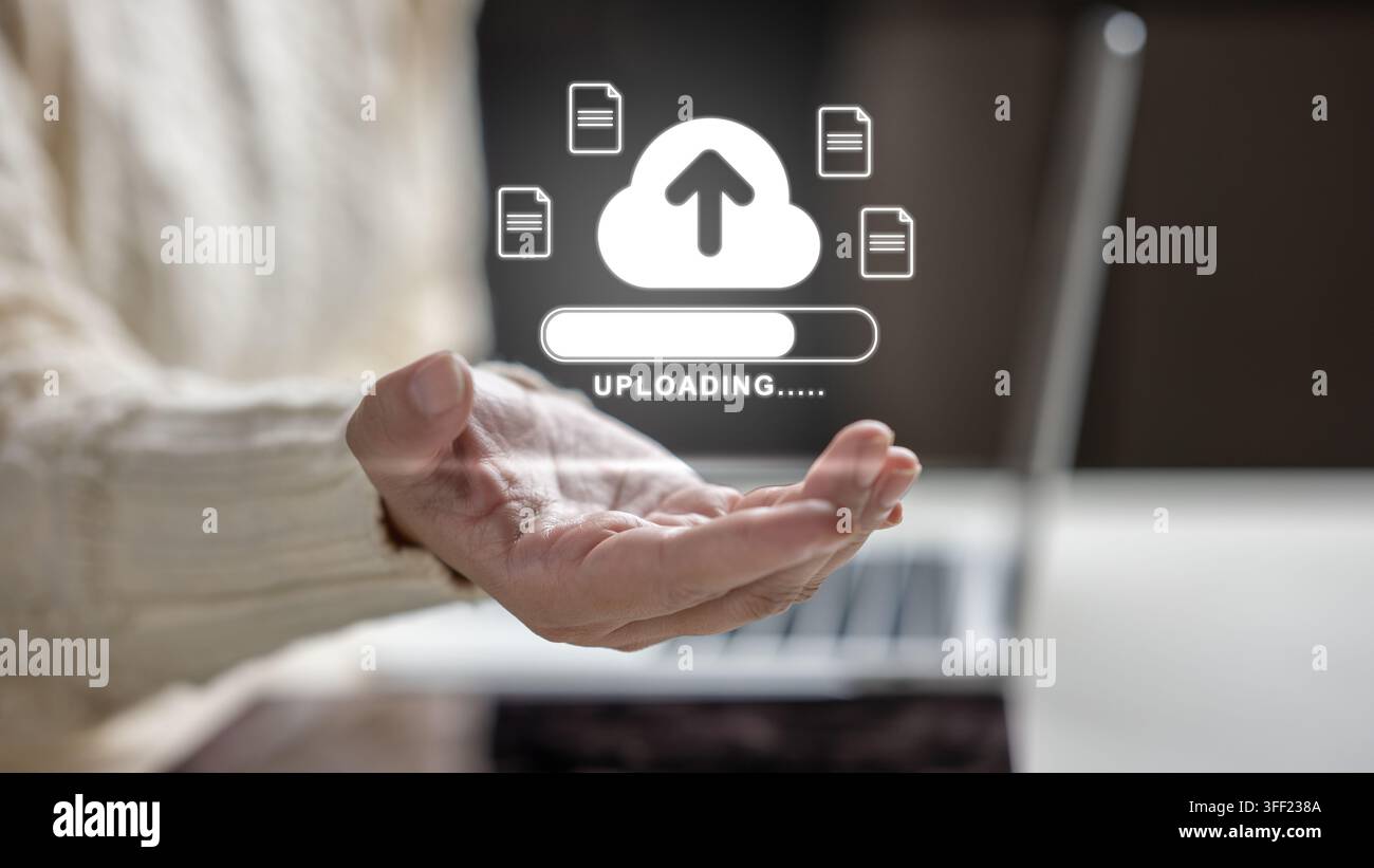 Mano femminile che tiene un'icona olografica di caricamento su cloud con simboli di file e una barra di avanzamento sopra un laptop. Concetto di archiviazione cloud computing e digitale Foto Stock
