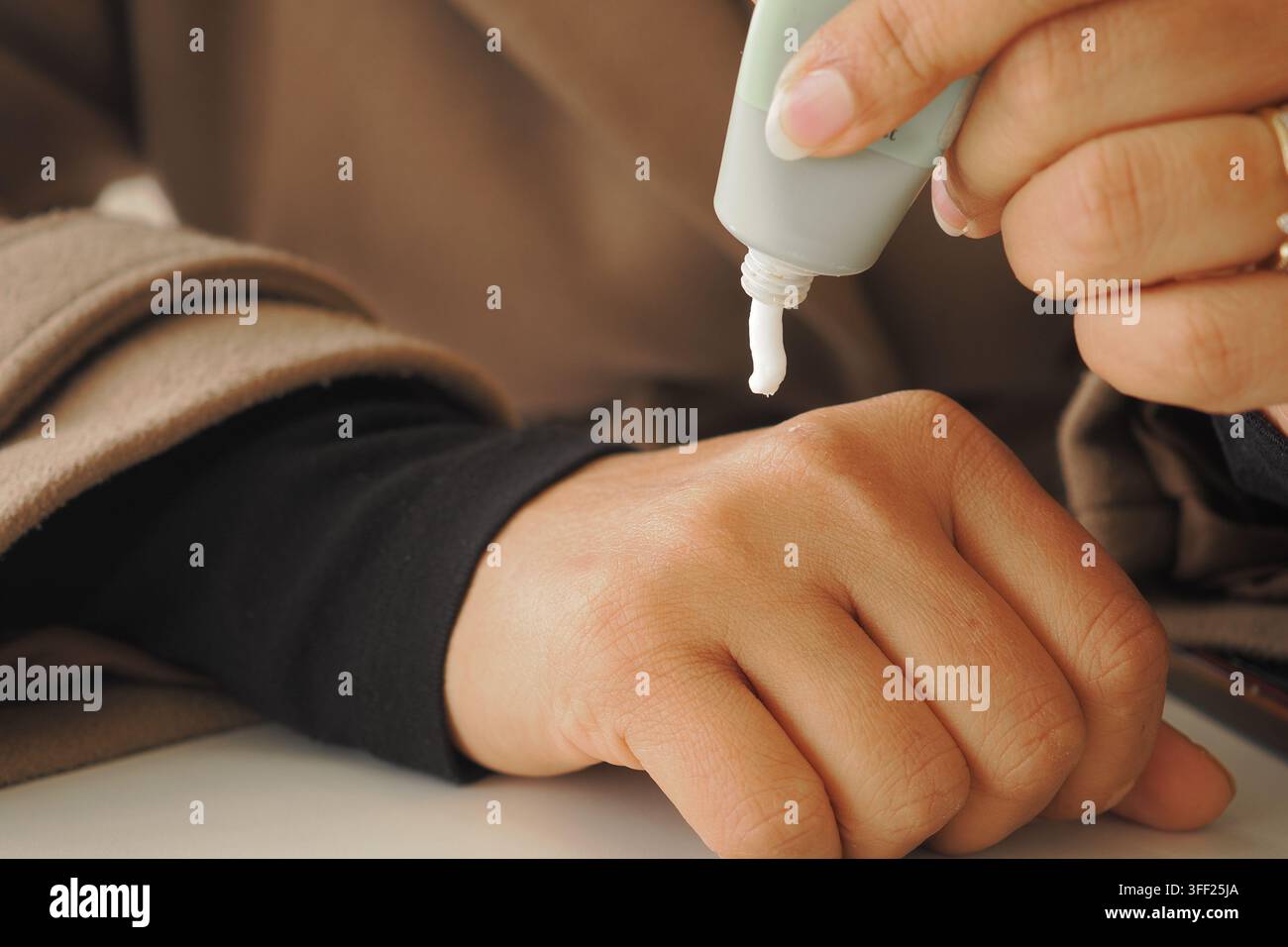 Applicare la crema alla mano in un semplice ambiente interno Foto Stock