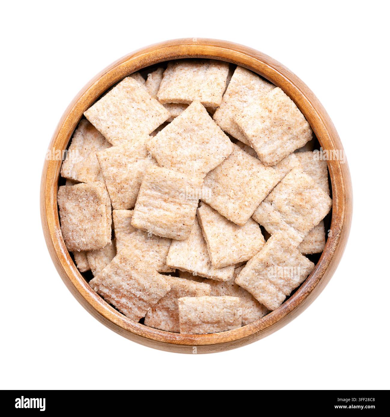 Quadrati croccanti alla cannella, cereali per la colazione in una ciotola di legno. Piccoli pezzi piatti fatti con farina integrale di grano e riso, con creste. Foto Foto Stock