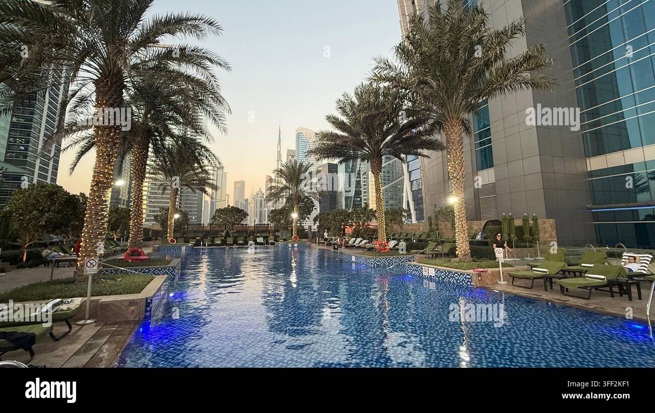 Ambientazione del primo pomeriggio sul Burj Khalifa alto, appartamenti e uffici moderni rialzati attorno al molo della piscina all'aperto illuminato al JW M - Immagine stock catturata con smartphone