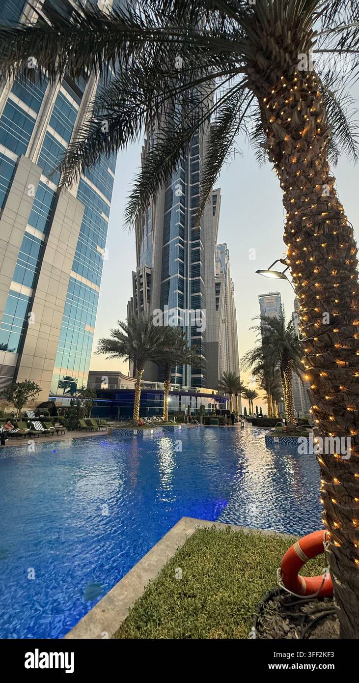 Ambientazione del primo pomeriggio sul Burj Khalifa alto, appartamenti e uffici moderni rialzati attorno al molo della piscina all'aperto illuminato al JW M - Immagine stock catturata con smartphone