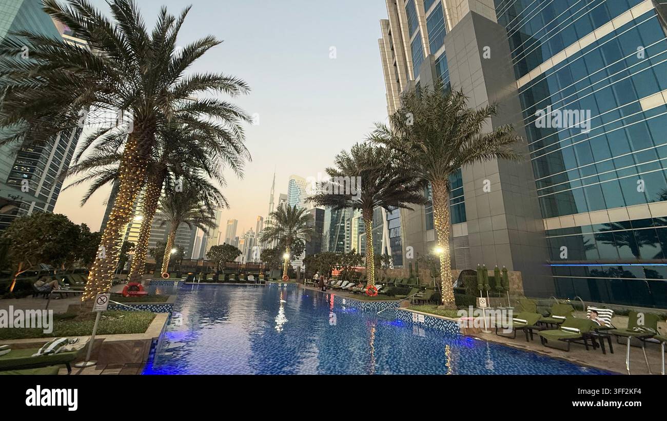 Ambientazione del primo pomeriggio sul Burj Khalifa alto, appartamenti e uffici moderni rialzati attorno al molo della piscina all'aperto illuminato al JW M - Immagine stock catturata con smartphone