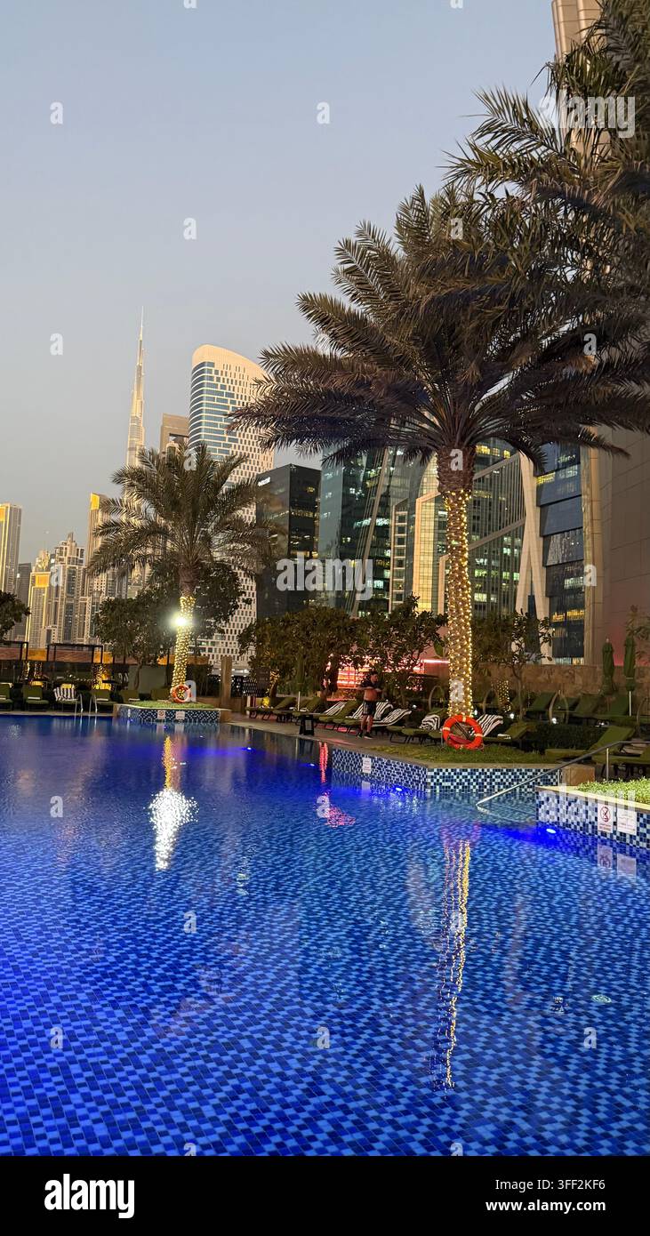 Ambientazione del primo pomeriggio sul Burj Khalifa alto, appartamenti e uffici moderni rialzati attorno al molo della piscina all'aperto illuminato al JW M - Immagine stock catturata con smartphone