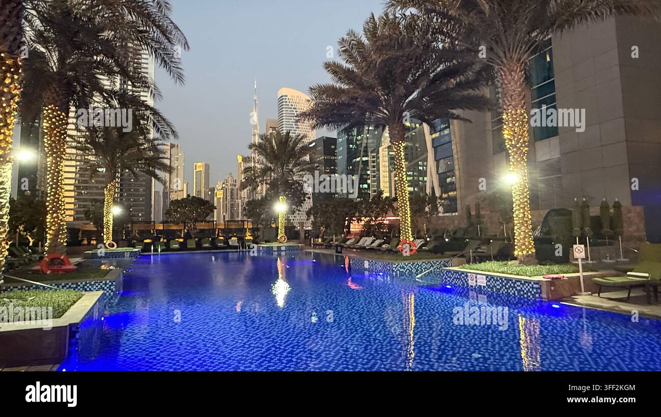 Ambientazione del primo pomeriggio sul Burj Khalifa alto, appartamenti e uffici moderni rialzati attorno al molo della piscina all'aperto illuminato al JW M - Immagine stock catturata con smartphone