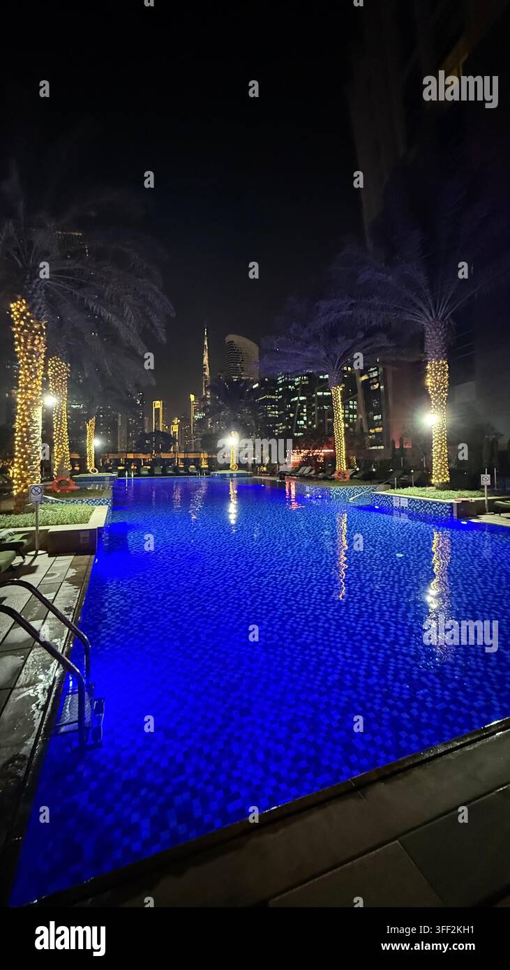 Ambientazione del primo pomeriggio sul Burj Khalifa alto, appartamenti e uffici moderni rialzati attorno al molo della piscina all'aperto illuminato al JW M - Immagine stock catturata con smartphone