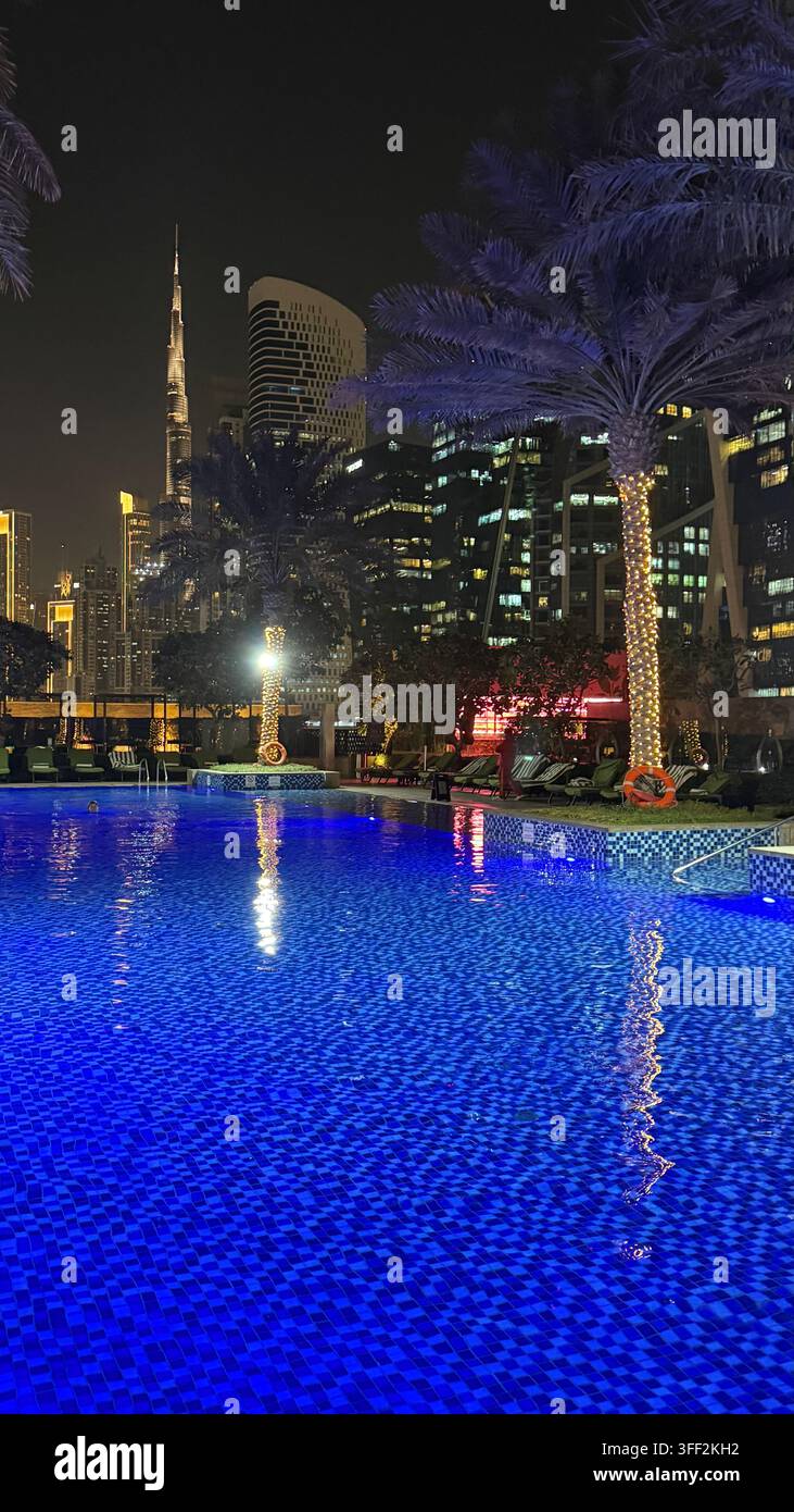 Ambientazione del primo pomeriggio sul Burj Khalifa alto, appartamenti e uffici moderni rialzati attorno al molo della piscina all'aperto illuminato al JW M - Immagine stock catturata con smartphone