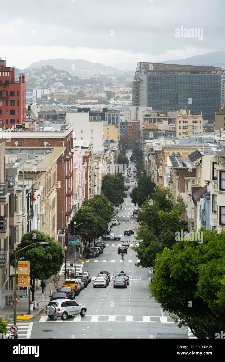 I pendolari guidano e camminano lungo Bush Street a San Francisco per i viaggi quotidiani sotto cieli nuvolosi, passando davanti all’edificio federale di San Francisco. Foto Stock