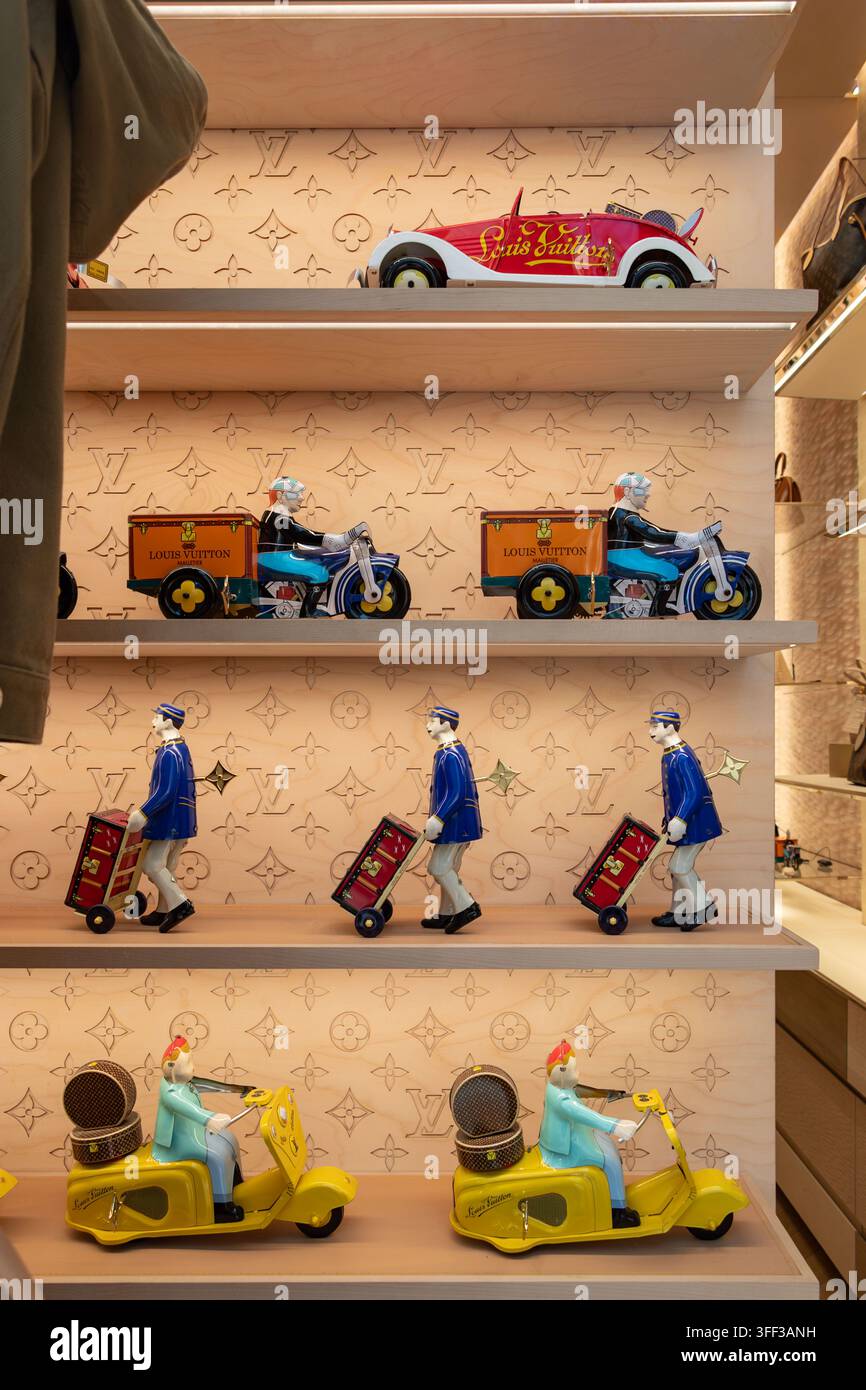 Esposizione in vetrina della boutique Louis Vuitton di giocattoli di latta su scaffali, inclusi giocattoli scooter, giocattoli moto e giocattoli auto Foto Stock