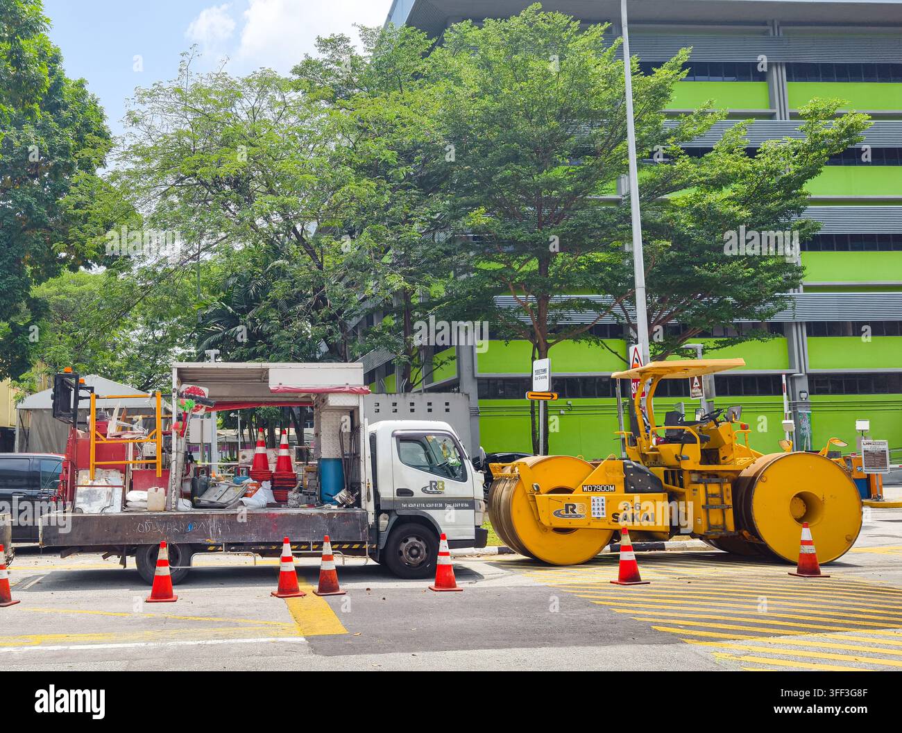 Camion pianale utilitario/merci carico di attrezzature, parcheggiato accanto a un rullo stradale pneumatico Sakai, lavori stradali in un hub nord, Singapore Foto Stock