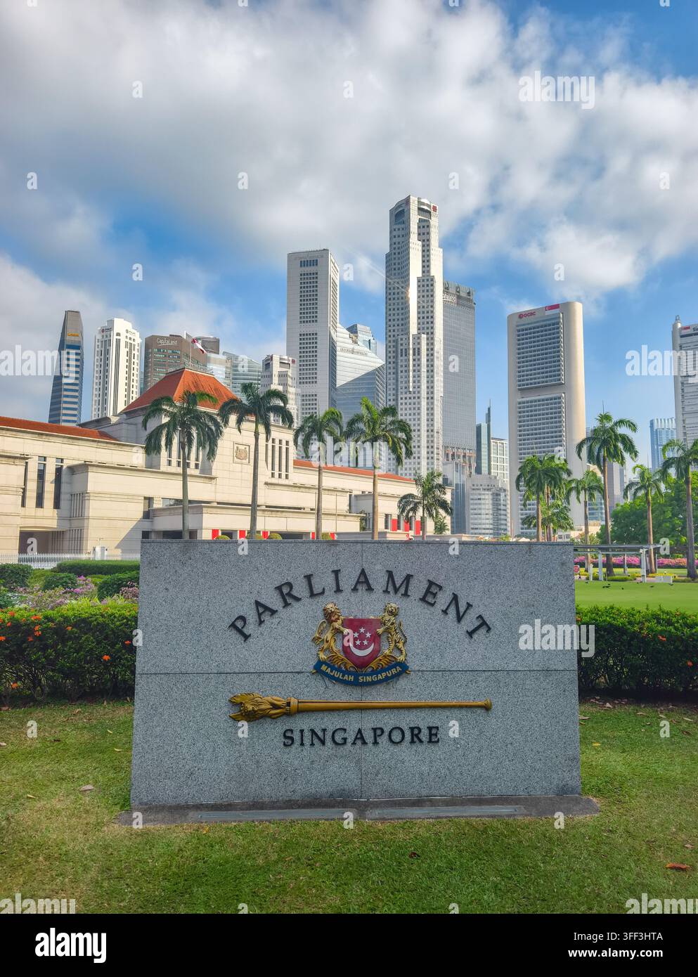 Pietra contrassegnata con "Parliament Singapore" accanto allo stemma nazionale e a un mazzuolo cerimoniale. Edificio del Parlamento e skyline sullo sfondo Foto Stock