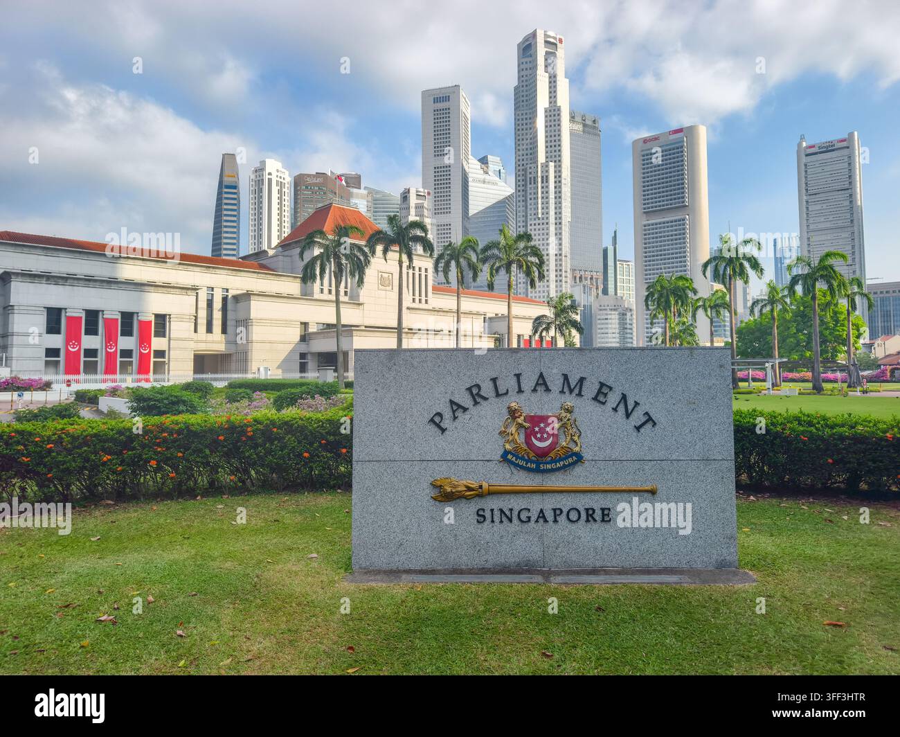 Pietra contrassegnata con "Parliament Singapore" accanto allo stemma nazionale e a un mazzuolo cerimoniale. Edificio del Parlamento e skyline sullo sfondo Foto Stock