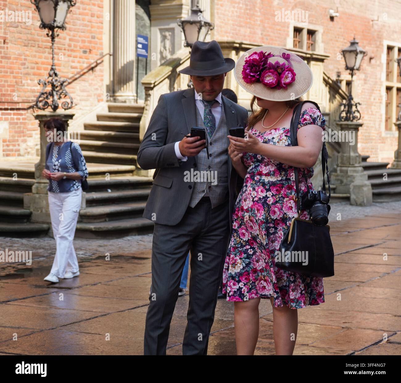 Coppia in moda vintage anni '40 che controlla gli smartphone vicino al Municipio durante la Fiera di San Domenico a Danzica, Polonia. Foto Stock