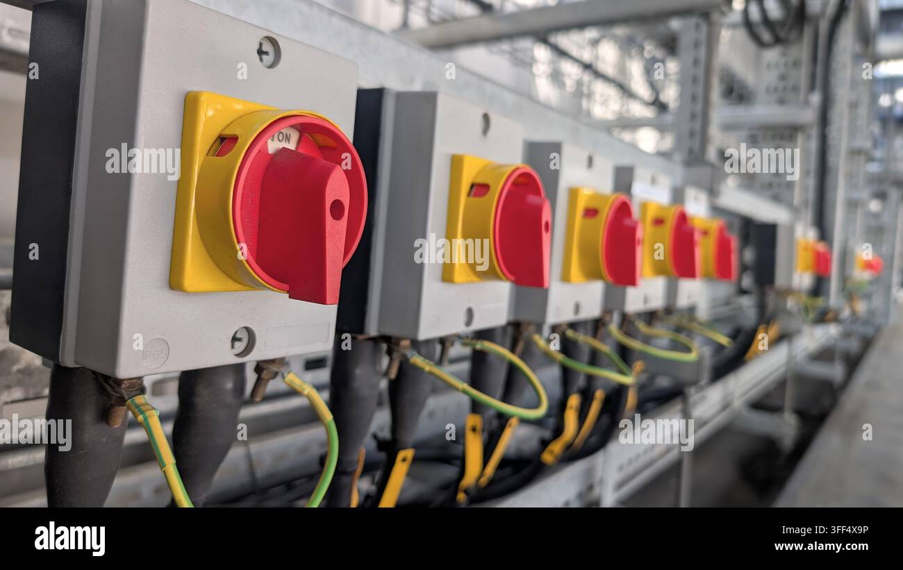 Prima vista di più interruttori isolatori rotativi rossi e gialli installati in un impianto industriale. Foto Stock