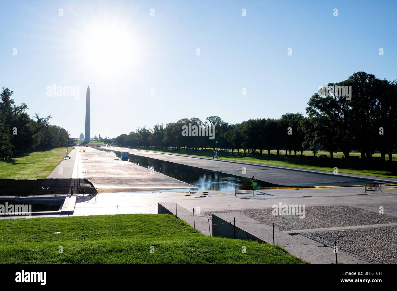 Lavoratori al Reflecting Pool vicino al Washington Monument a Washington DC | WASHINGTON, D.C. — Lavoratori curano il Reflecting Pool parzialmente svuotato del Lincoln Memorial sul National Mall, domenica 6 settembre 2026, con il Washington Monument e la cupola del Campidoglio degli Stati Uniti visibili in lontananza. Henry Bacon progettò il bacino, completato nel 1922-1923 come elemento idrico assiale del piano McMillan. Un progetto di risanamento avviato nell’aprile 2026 ha mantenuto il bacino svuotato per mesi dopo che il suo nuovo rivestimento si è staccato e le alghe si sono diffuse. I costi sono aumentati oltre i 19 milioni di dollari tra tre appaltatori, con un quarto aggiunto in lat Foto Stock