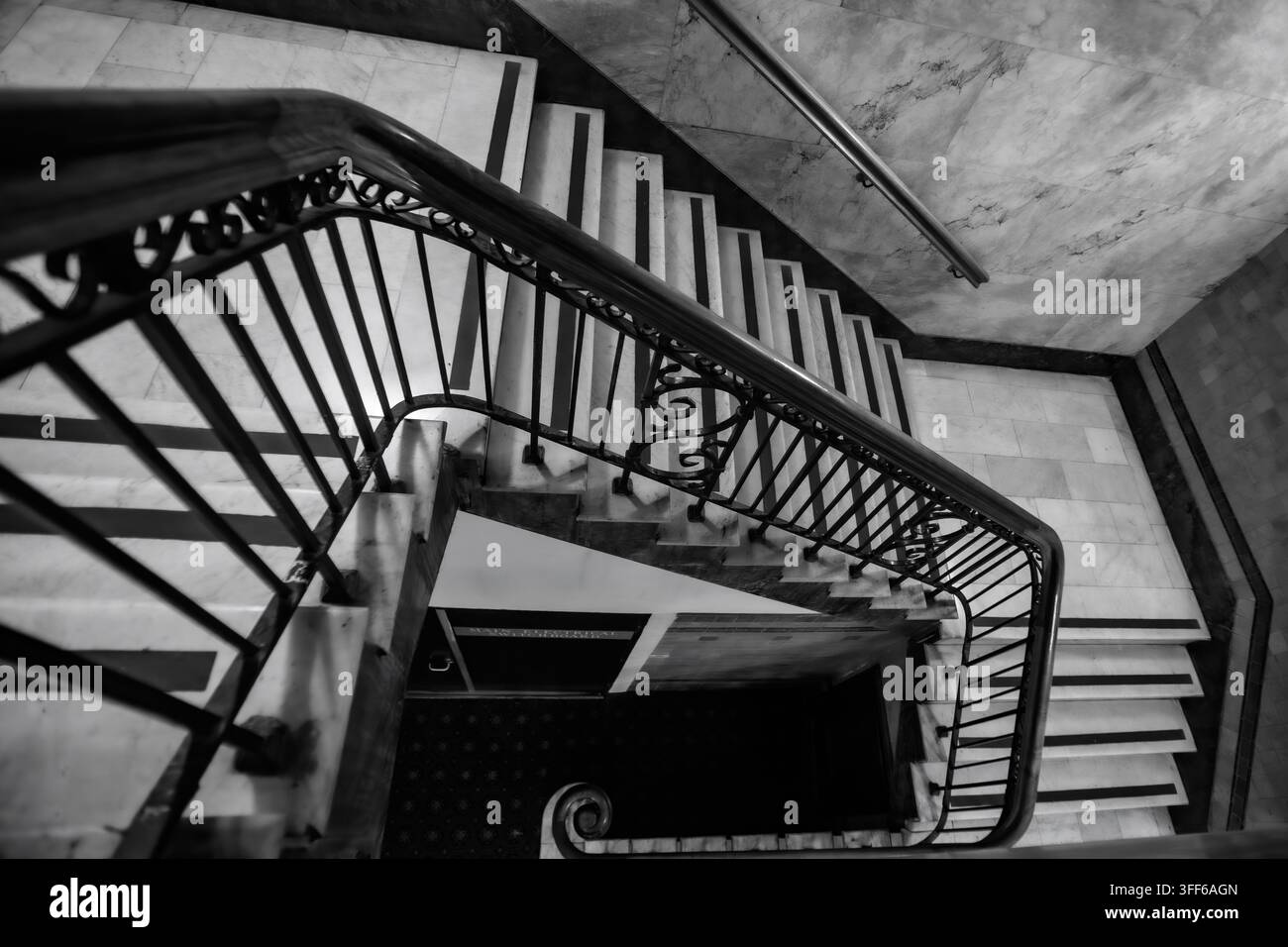 Vista in bianco e nero ad angolo alto di una storica scala in marmo con ringhiera in ferro battuto. Foto Stock