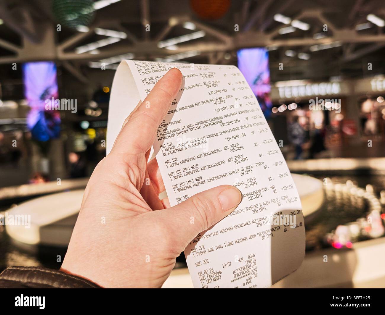 Kirov, Russia – 8 febbraio 2026: Una persona tiene uno scontrino della spesa con i dettagli del pagamento e degli articoli acquistati in un supermercato durante un intenso momento di shopping Foto Stock