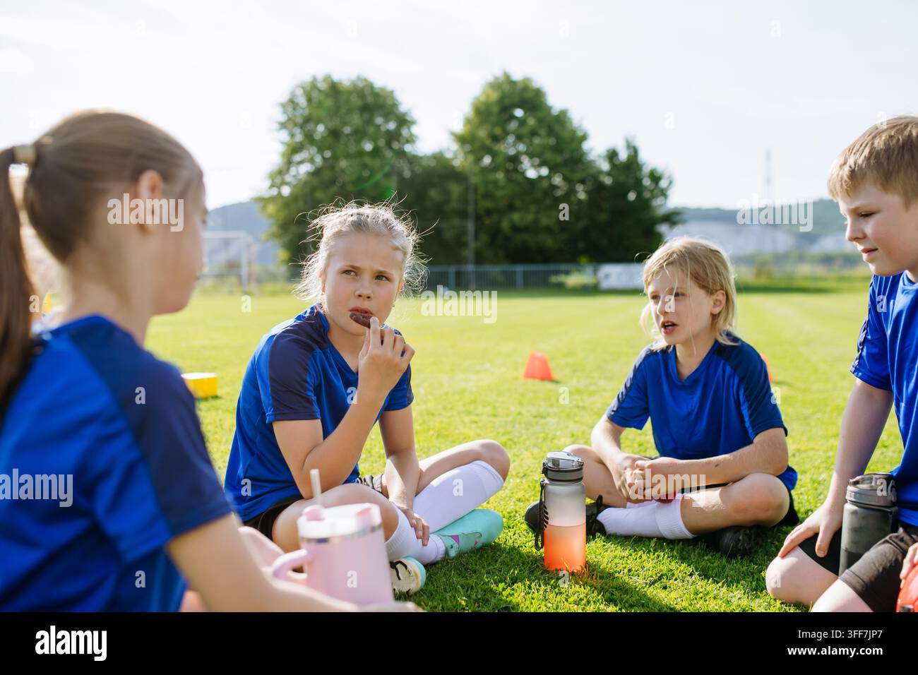 I bambini si rilassano insieme dopo l'allenamento e l'esercizio calcistico giovanile. Foto Stock