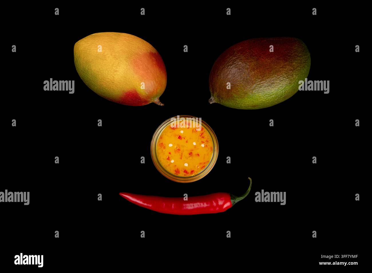 Faccia sorridente fatta di peperoncino, mango e salsa al peperoncino e mango su sfondo nero Foto Stock
