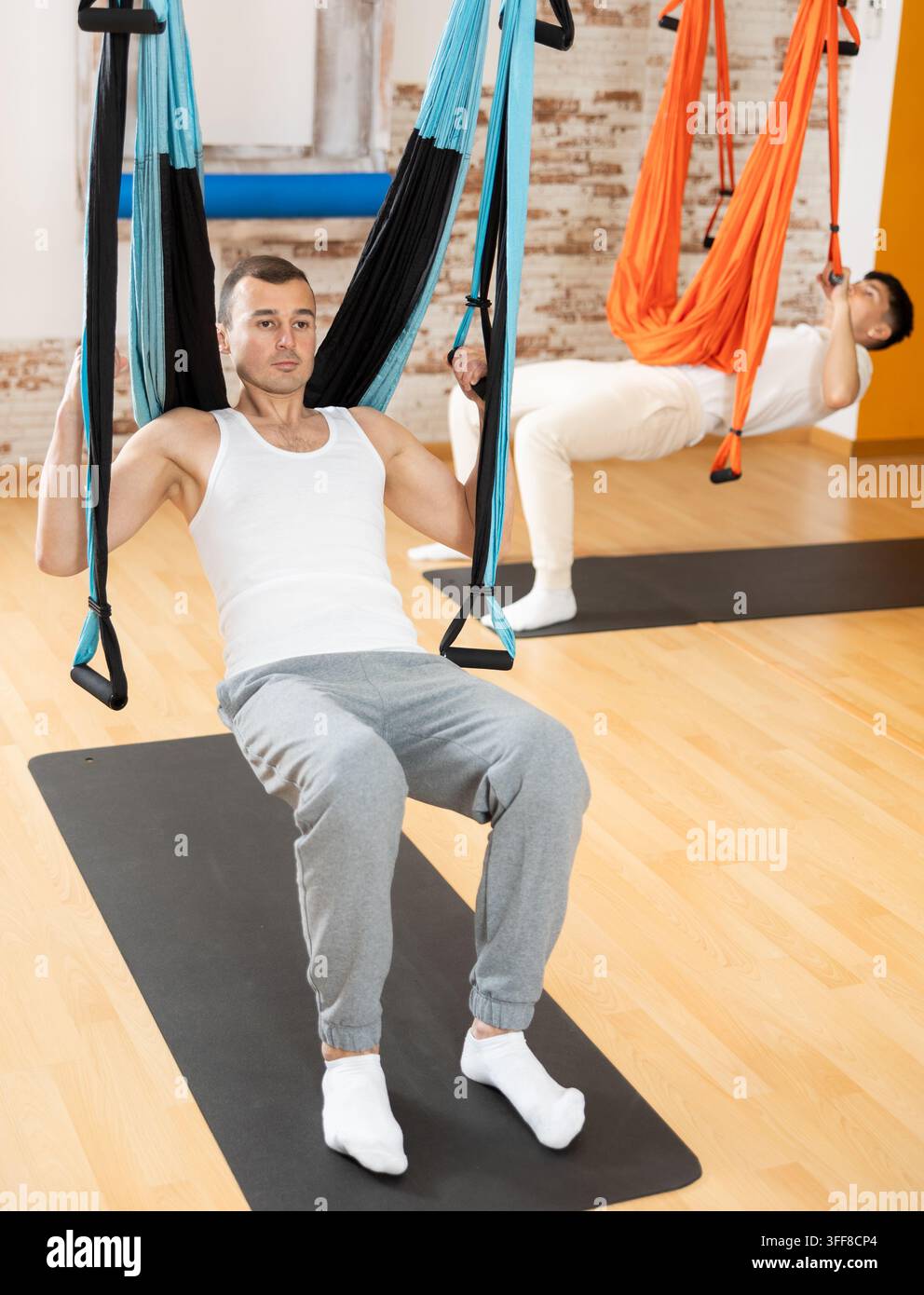 Visitatore uomo esegue esercizi in posizione sospesa su sling di Pilates. Sviluppo della forza muscolare, equilibrio con l'aiuto di un carico multidirezionale. Spor Foto Stock