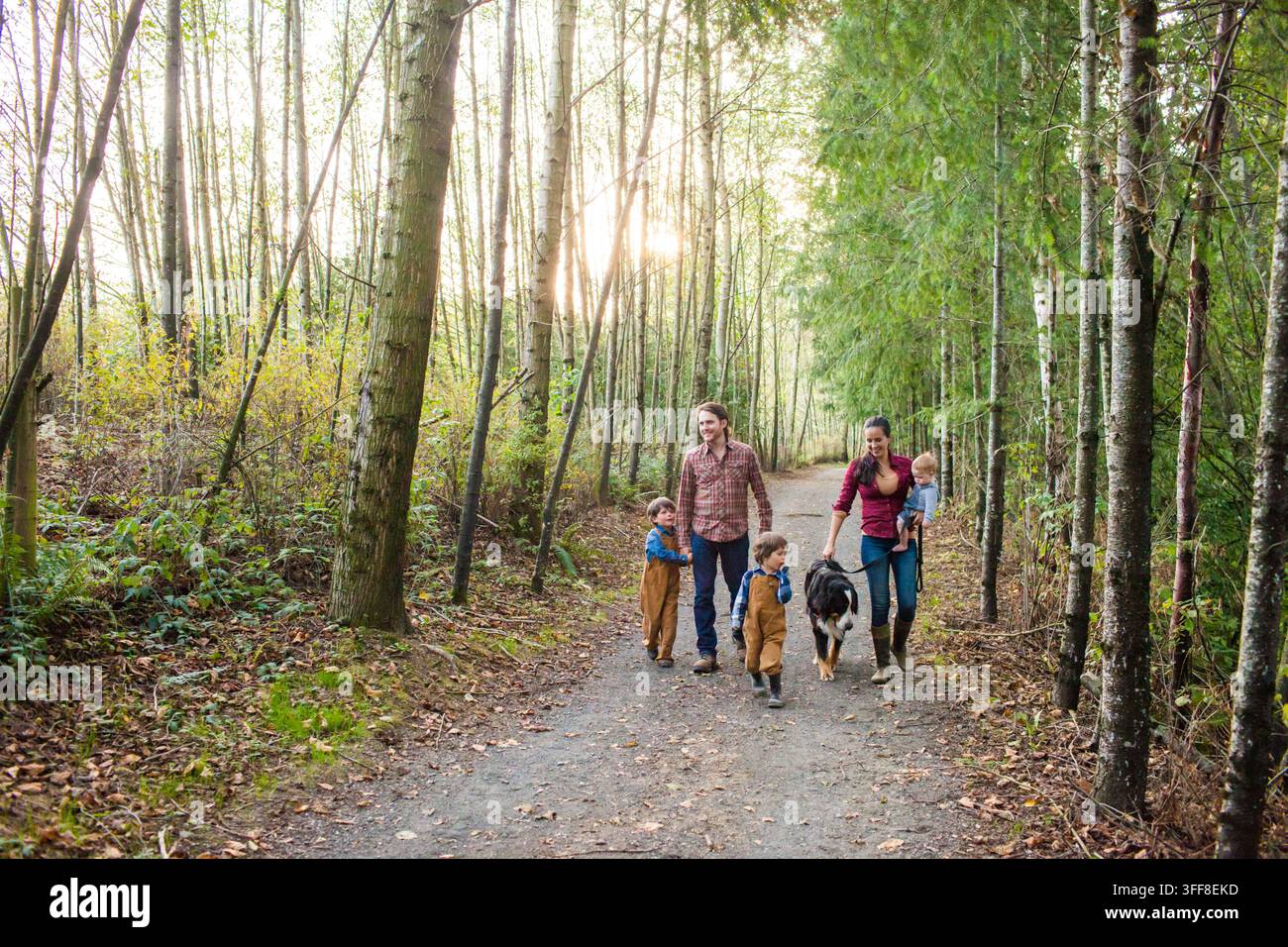 Famiglia felice e cane si godono una passeggiata nel bosco Foto Stock