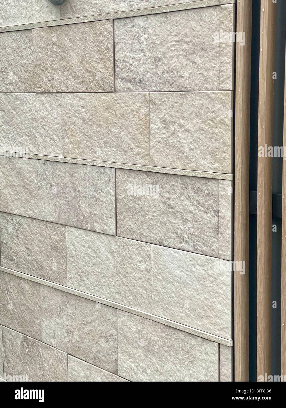 Dettaglio di un esterno residenziale giapponese moderno con rivestimenti murali a texture di pietra chiara e finiture in legno, design contemporaneo di casa in Giappone. Foto Stock