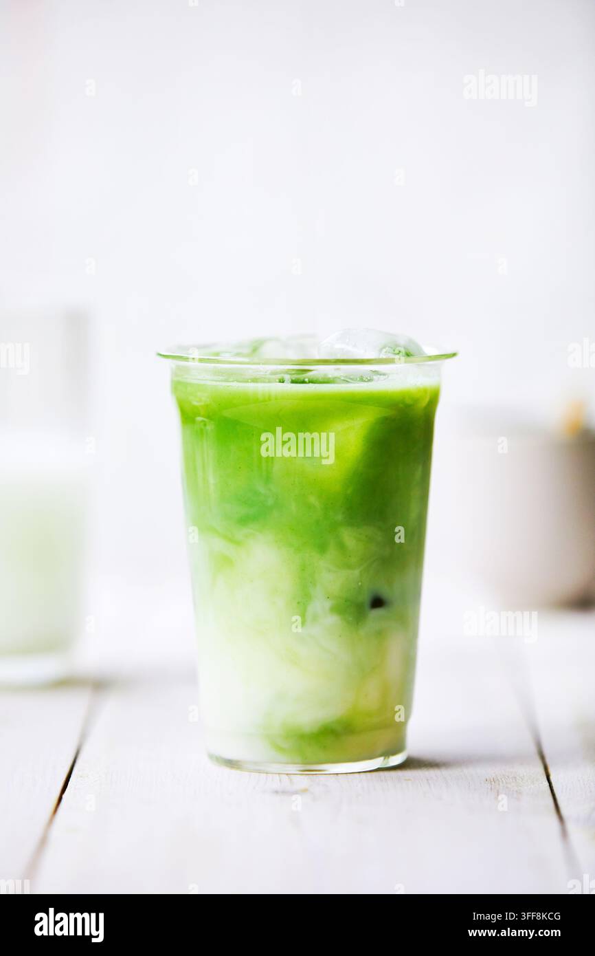 Latte matcha in un bicchiere. Matcha e latte si mescolano. Atmosfera di cucina luminosa, fresca e amichevole. Foto Stock