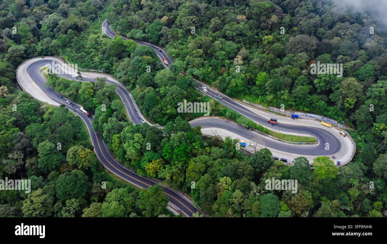 Vista aerea della strada tortuosa Penatapan Berastagi circondata da una rigogliosa foresta verde a Sibolangit, nel nord di Sumatra, Indonesia. Foto Stock