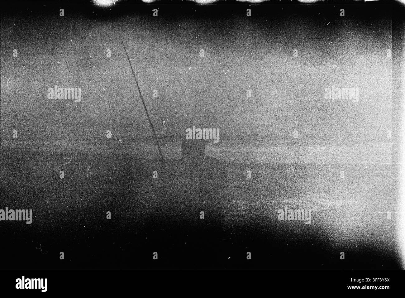 Granulato denso, graffi, polvere e una perdita di luce irregolare creano una texture di film monocromatica astratta con un aspetto archivistico disteso. Foto Stock