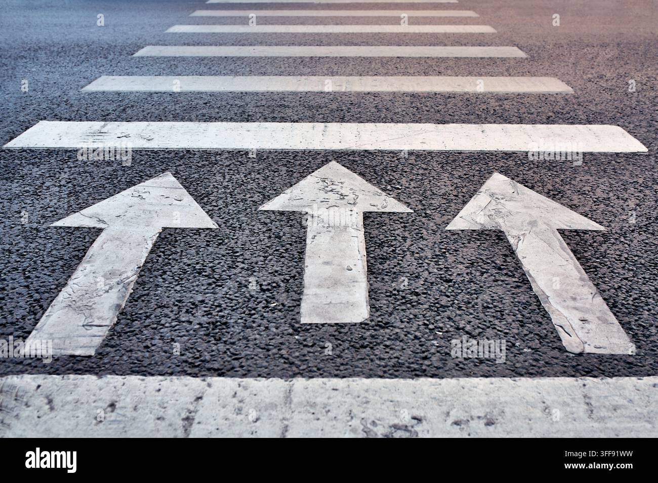 Tre frecce dipinte sull'asfalto che puntano in avanti, simboleggiando direzione, progresso, motivazione Foto Stock