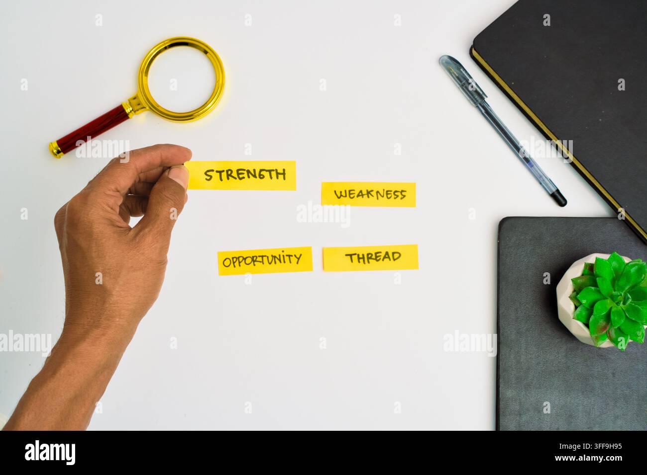 Una mano organizza etichette di analisi SWOT su una scrivania bianca pulita per la pianificazione della strategia aziendale. Foto Stock