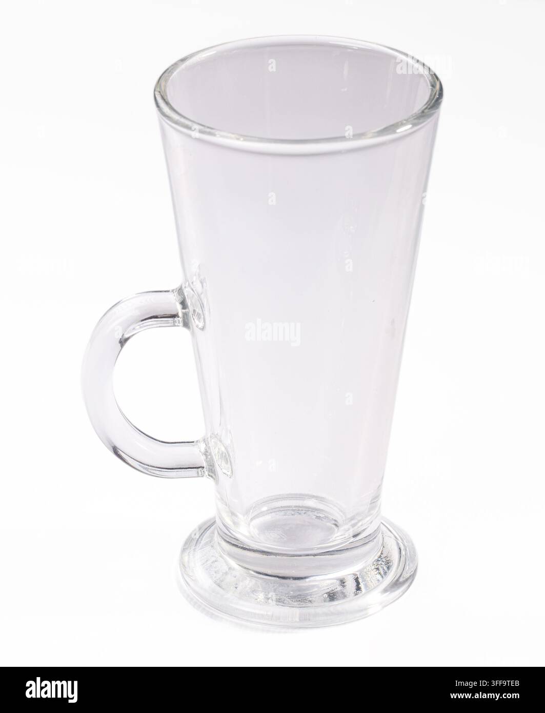 Tazza di vetro trasparente con manico curvo e base stabile, scattata su sfondo bianco puro con illuminazione uniforme. Ideale per mockup di bevande, estetica pulita, spazio per il testo Foto Stock