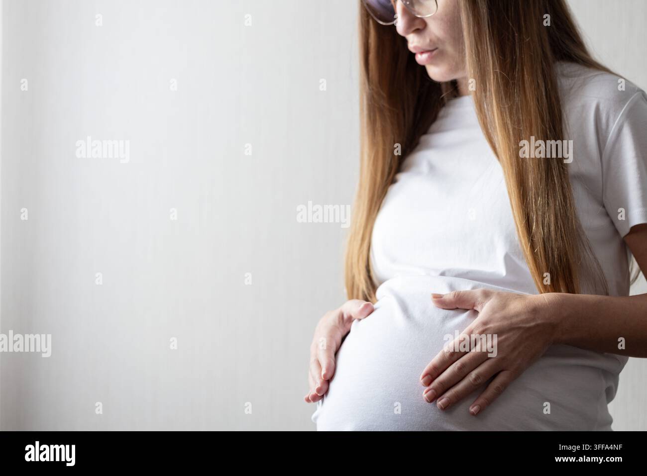 Donna incinta mette le mani sul ventre e fa esercizi di respirazione. Foto Stock