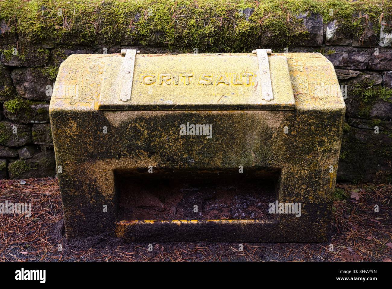 Cestino di pietrisco e sale in pietra erosa coperto di muschio, posizionato contro una vecchia muraglia a secco vicino al ponte di Barrow, Bolton, Greater Manchester, Regno Unito. Foto Stock