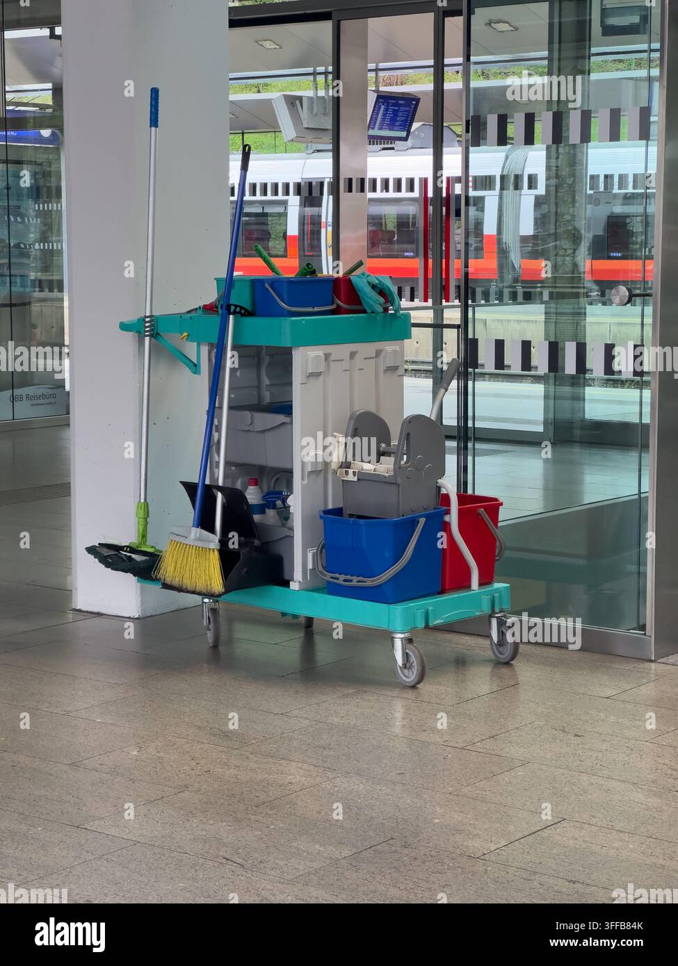 Carrello per la pulizia con scope, secchi e supporti per mocio all'interno di una stazione ferroviaria. Concetto di igiene, manutenzione, servizio e organizzazione e cura del posto di lavoro Foto Stock