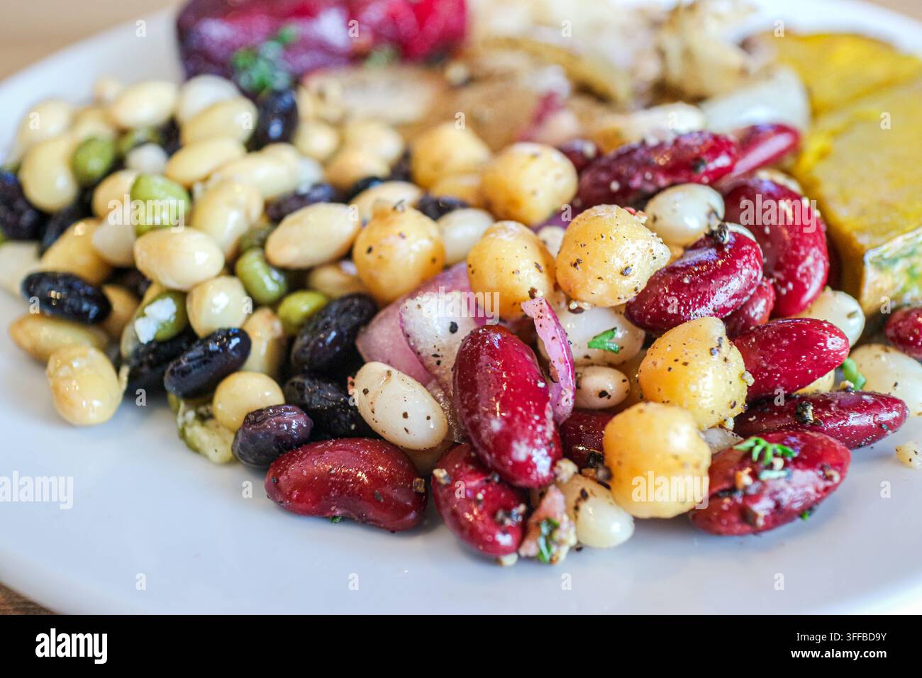 Prima pianata di un'insalata di cinque legumi con fagioli neri, fagioli bianchi, fagioli rossi, ceci e cipolla rossa su un piatto in Thailandia. Foto Stock