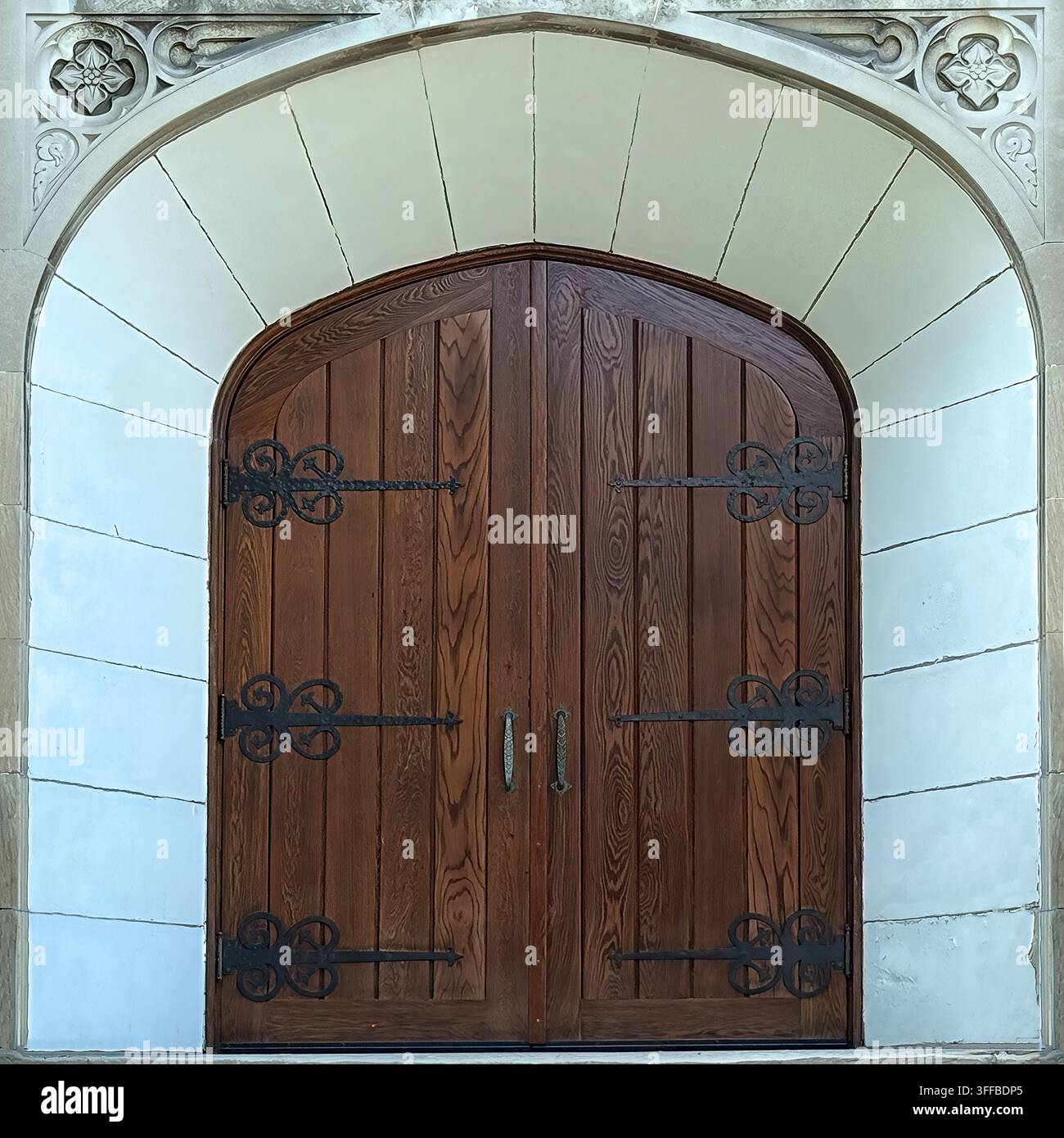 Porte doppie in legno in stile gotico con cerniere decorative in ferro inserite in un ingresso in pietra intagliato a Chicago. Foto Stock