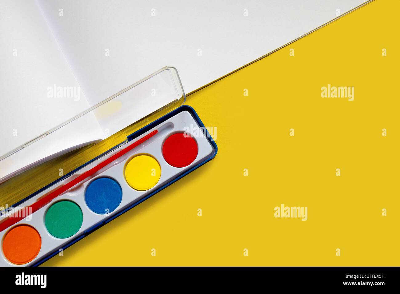 Palette di pittura ad acquerello colorata e pennello su sfondo giallo brillante Foto Stock