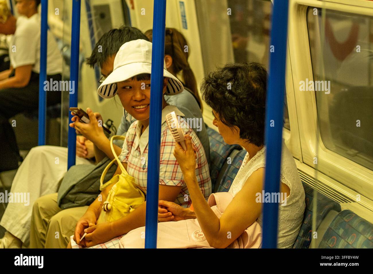 LONDRA – 25 GIUGNO 2026: Northern line tube – Passeggeri che usano un ventaglio portatile durante l’ondata di caldo estiva. Foto Stock