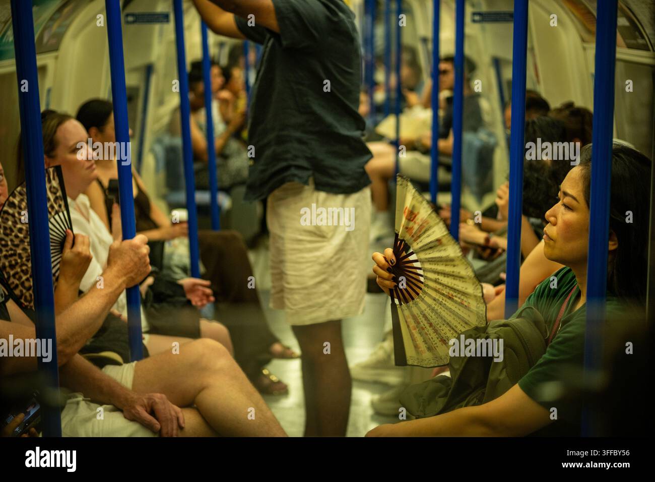 LONDRA – 25 GIUGNO 2026: Northern line tube – Passeggeri che usano un ventaglio portatile durante l’ondata di caldo estiva. Foto Stock