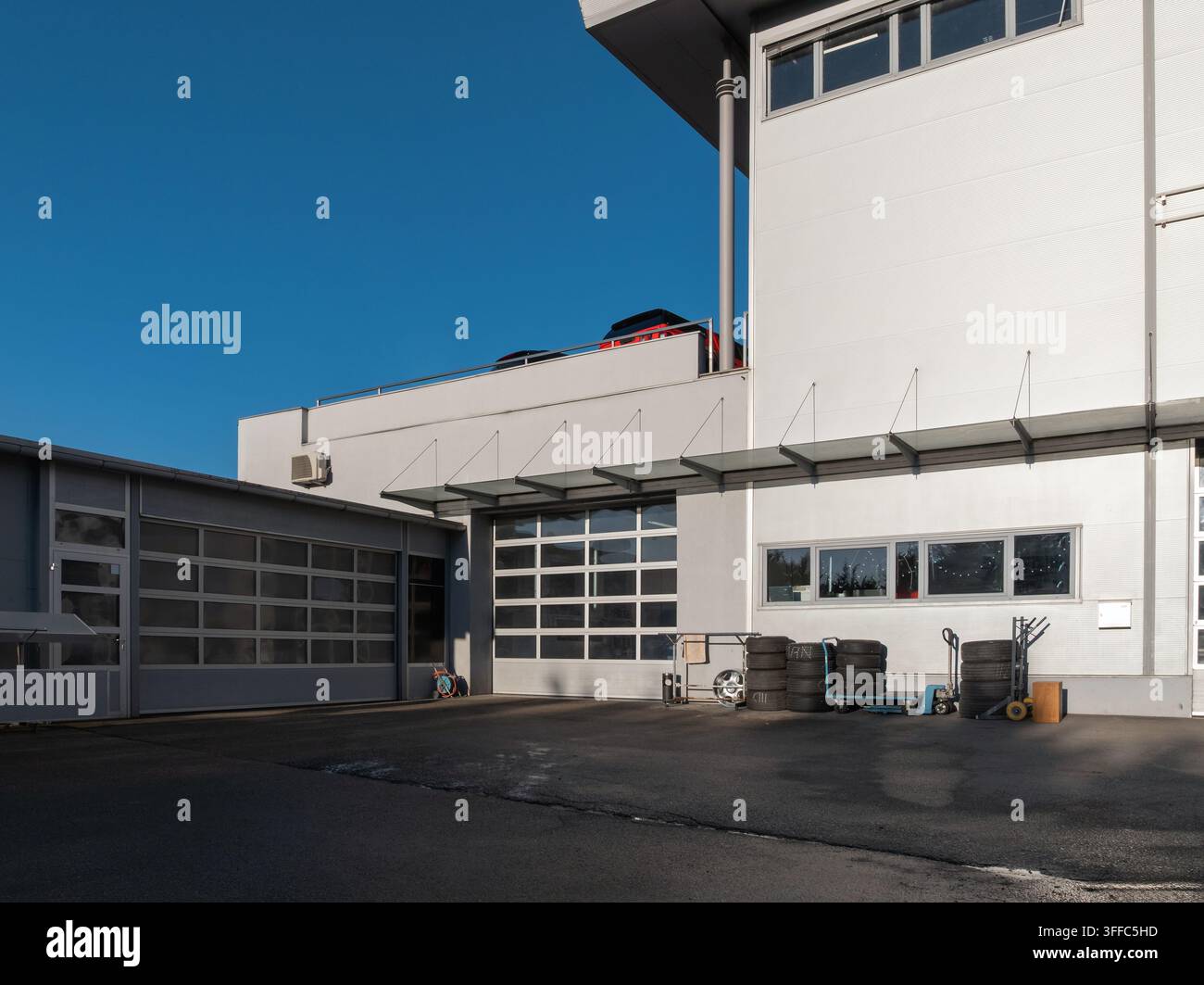 Questa officina meccanica mostra l'esterno dell'edificio con porte di servizio e pneumatici all'esterno. È una giornata luminosa e soleggiata. Foto Stock