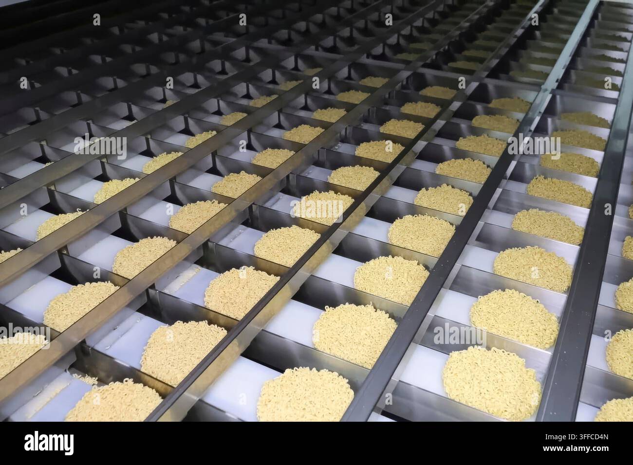 Linea di produzione istantanea di spaghetti. porzioni di spaghetti sul trasportatore, industria alimentare di massa. Foto Stock