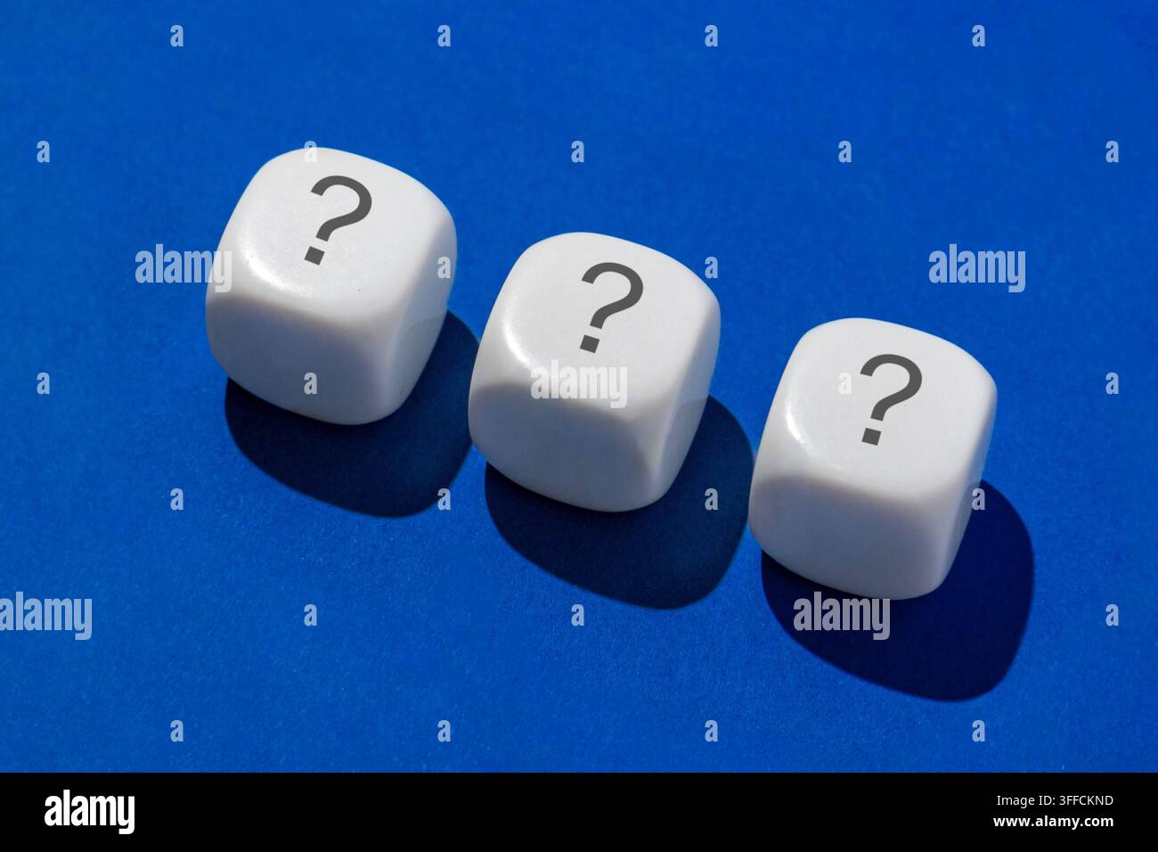 Tre dadi bianchi con punti interrogativi su uno sfondo blu. Processo decisionale, incertezza, valutazione del rischio, concetto di strategia. Foto Stock