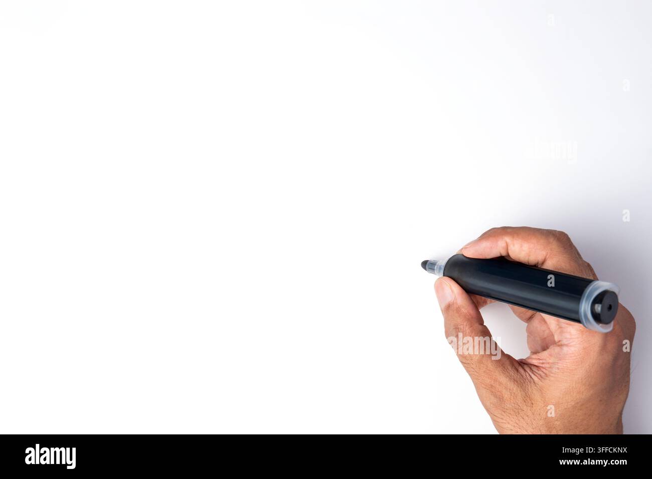 Mano che tiene una penna marcatore nera per scrivere su uno sfondo bianco vuoto. Spazio per il testo. Foto Stock
