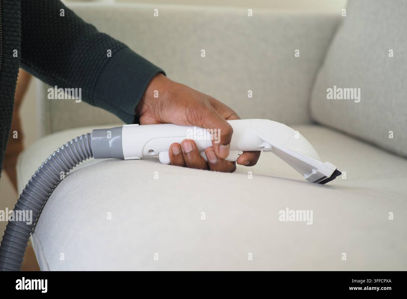 Persona che pulisce un divano con uno strumento per l'aspirazione Foto Stock