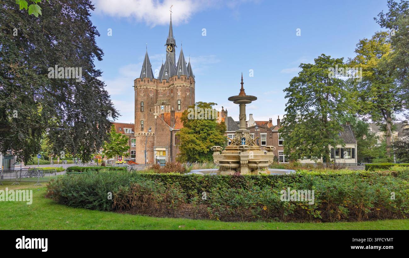 Zwolle, Paesi Bassi – 23 agosto 2026 – Vista panoramica del parco con la fontana storica di Van Nahuys che scorre e la porta monumentale medievale di Sassenpoort Foto Stock