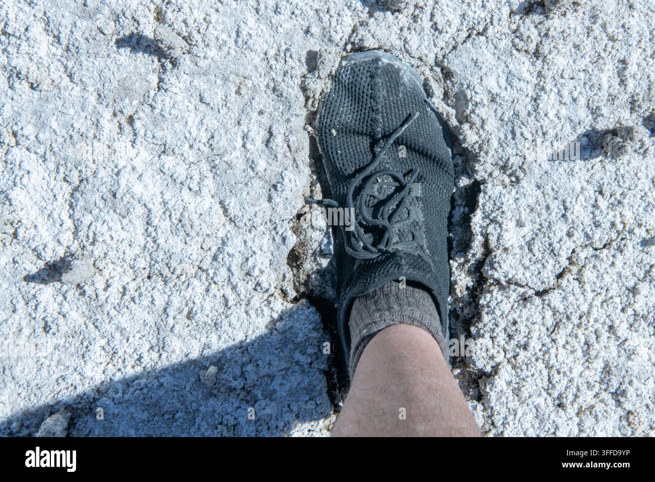 Un piede poggia su una pampa alcalina sulla riva di un lago di soda dove i depositi minerali hanno lasciato un residuo polverulento asciutto. Foto Stock