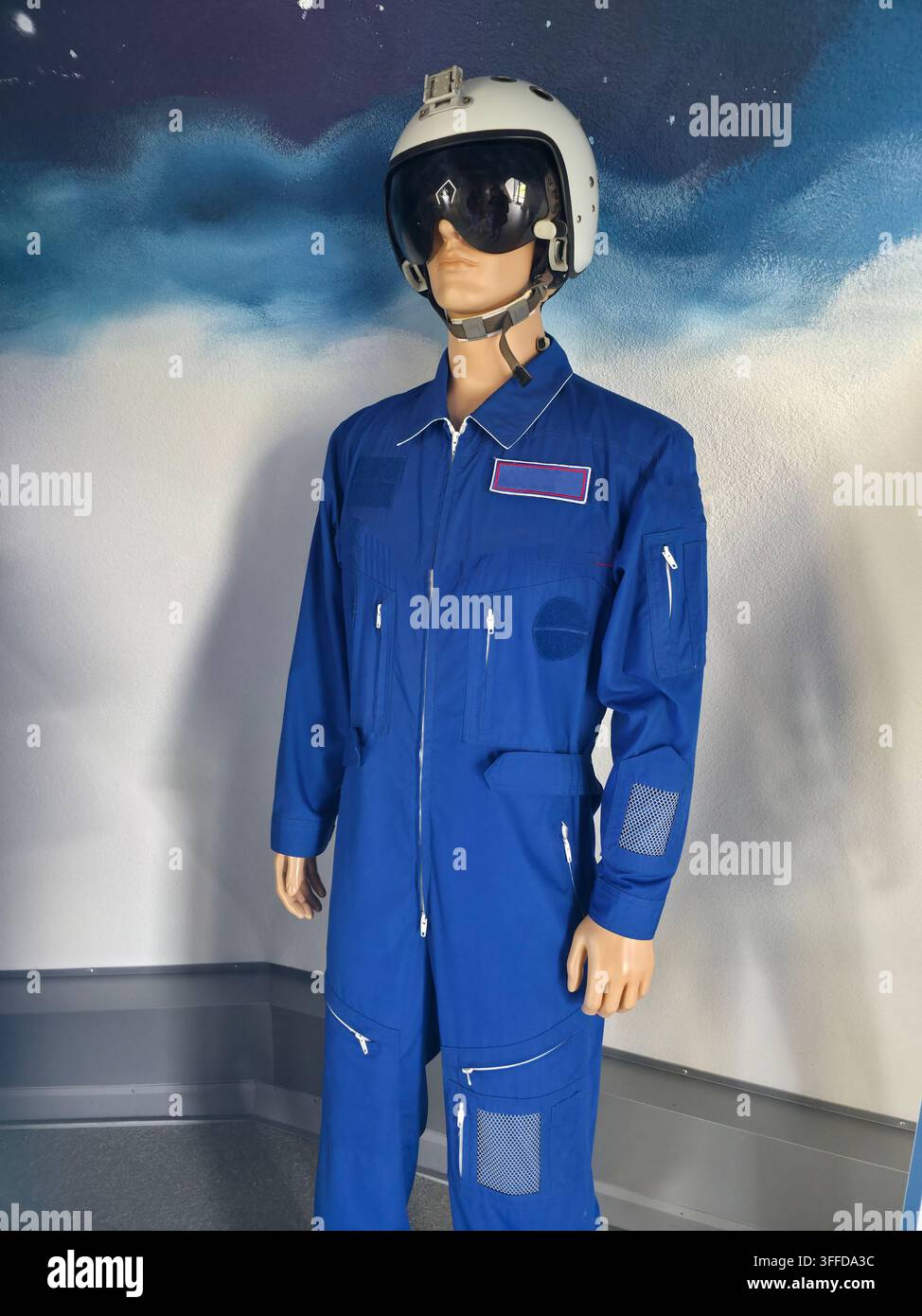 Vista completa di un manichino che mostra una moderna tuta da volo o astronautica blu. La tuta presenta accenti a strisce rosse, bianche e blu prominenti sul petto Foto Stock