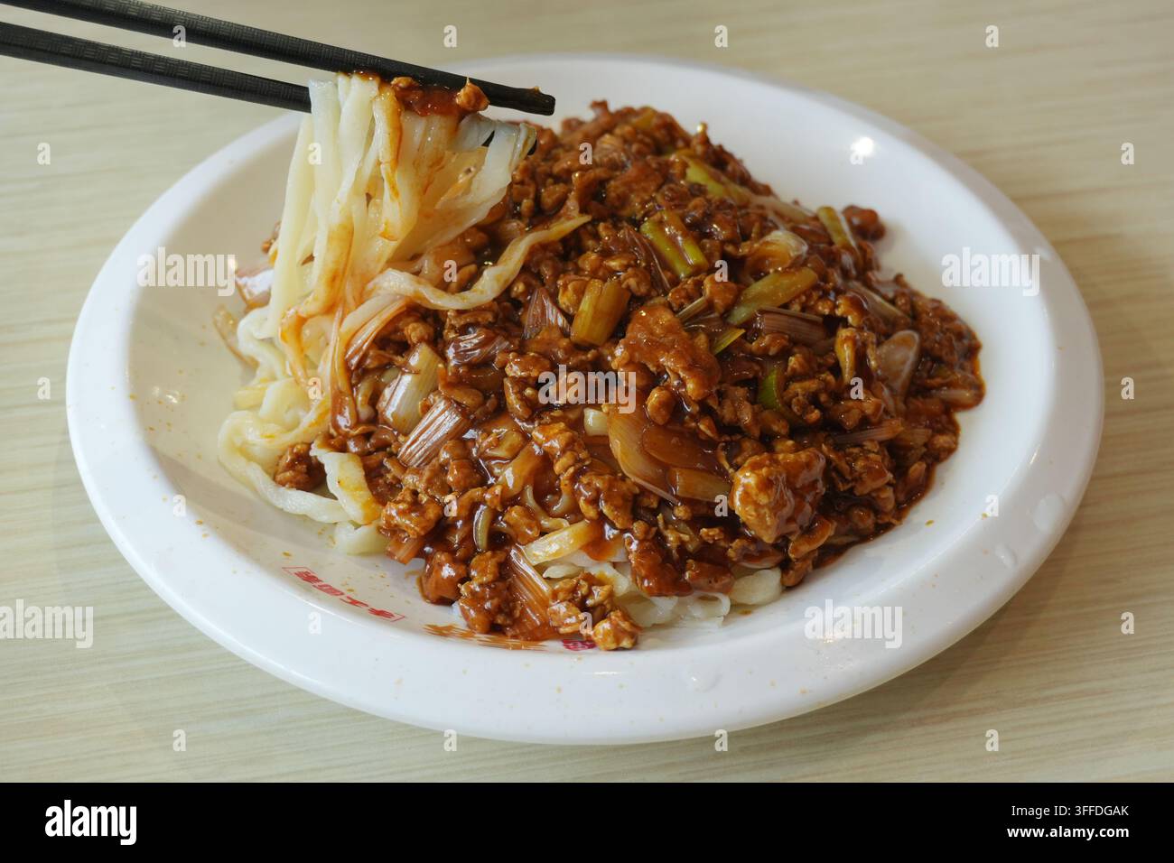 Noodles al suino tritato sollevati con le bacchette, piatto di noodles di un ristorante Foto Stock